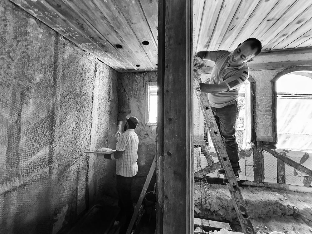 Ouvrier projetant de l'isolant dans des combles anciens